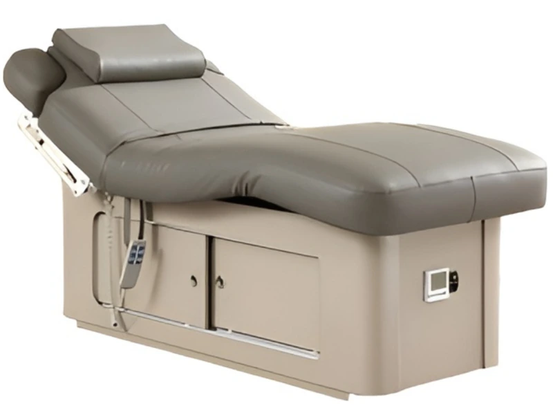 Grey electric treatment bed with a raised back section and a hand control on the side